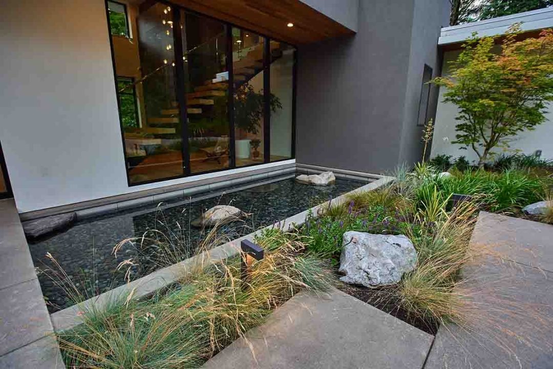 Modernist natural pond and plants - 7 Dees Landscaping Modern rectangular pond water feature with natural rocks, against a house - 7 Dees Landscaping
