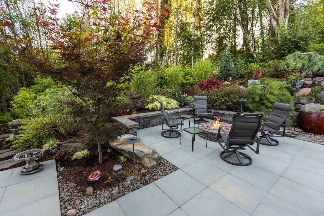 Patio with charis, fire pit, and lush shade garden - 7 Dees Landscaping