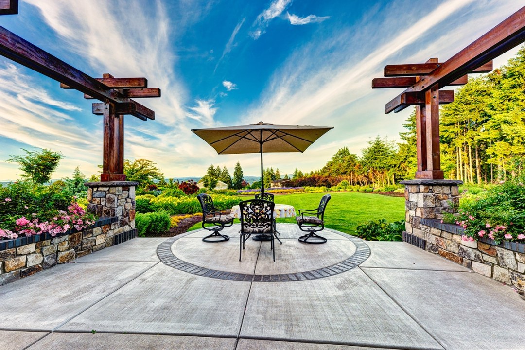 Poured concrete patio with table and chairs and pergola walls - 7 Dees Landscaping