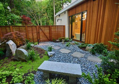 bench and stone pathway with shade plants and wood fence