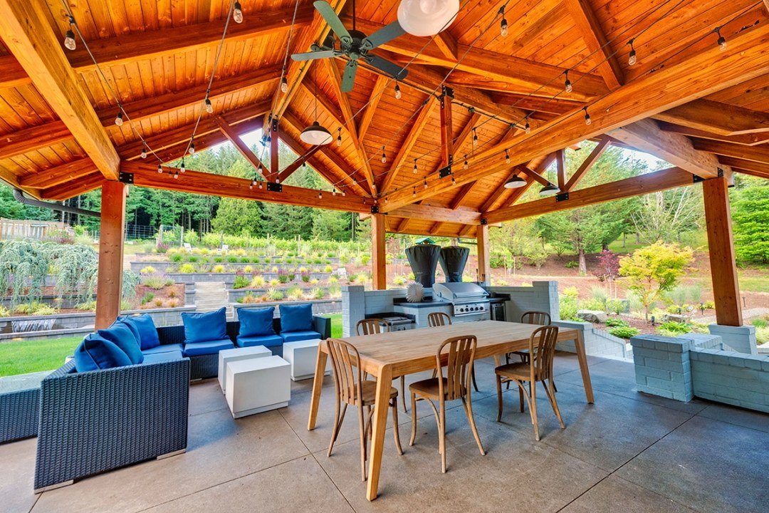 Outside living with kitchen and seating in a backyard with lawn and sloped plantings - Dennis' 7 Dees Landscaping in Portland View from an outdoor seating area and kitchen overlooking backyard grass and plantings - Dennis' 7 Dees Landscaping in Portland