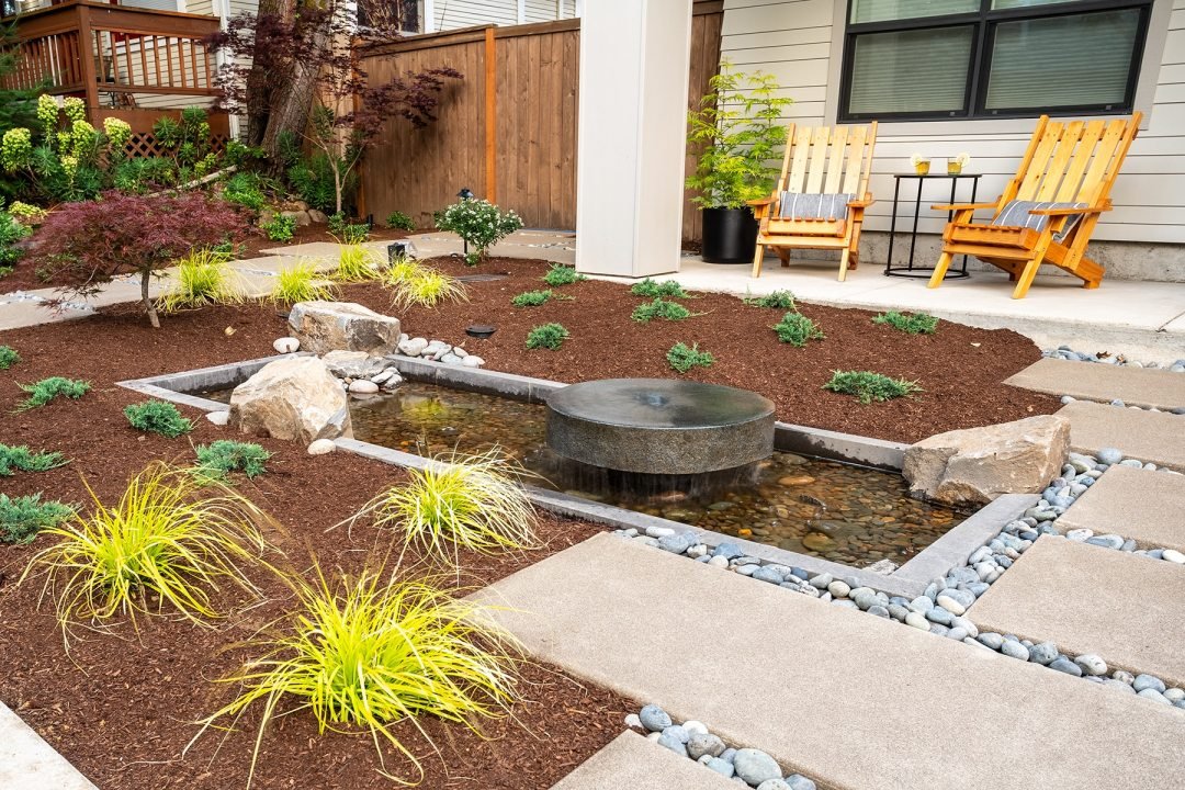 Custom round stone water feature with plantings - 7 Dees Landscaping Custom water feature reflection pool with mill stone and modern plantings - 7 Dees Landscaping
